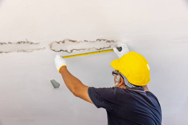 Person measuring the size of the leaking ceiling