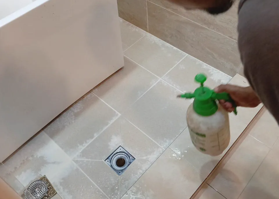 Person spraying waterproofing products onto tiles